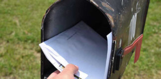 Hand placing mail in a black mailbox