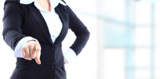 A professional woman in a suit pointing with her right hand