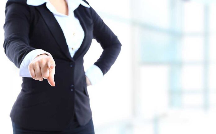 shutterstock_157259495.jpg A professional woman in a suit pointing with her right hand