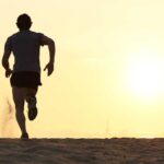 Silhouette of a man running on the beach during sunset