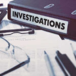 Documents and binder labeled Investigations on desk.