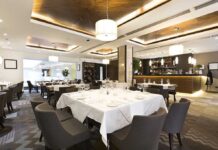 Interior of a modern restaurant with elegantly set tables and a bar area