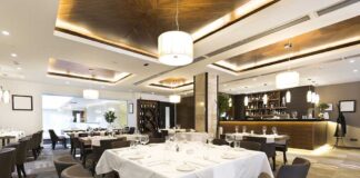 Interior of a modern restaurant with elegantly set tables and a bar area