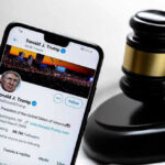 Smartphone displaying Twitter profile near a judges gavel.