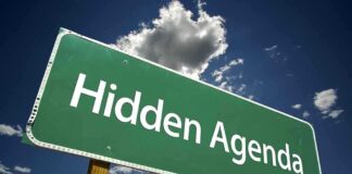 Road sign displaying the phrase Hidden Agenda against a blue sky