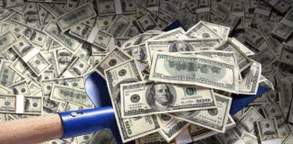 A shovel filled with stacks of cash on a background of scattered dollar bills