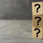 Three wooden blocks with question marks stacked.