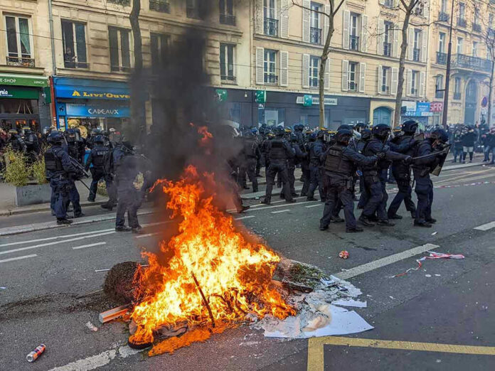 Protesters and police clash; fire in the street.