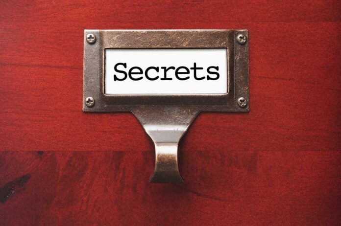 A label holder on a wooden surface with the word Secrets displayed