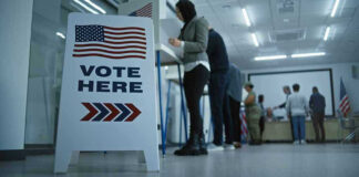 Sign reading Vote Here in a polling station.