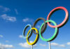 Olympic rings sculpture against blue sky.