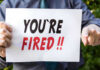 Person holding YOURE FIRED sign.