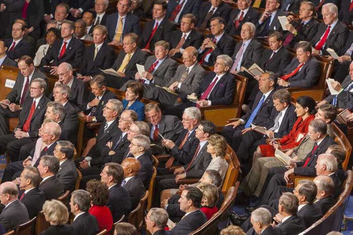 492045043 Audience of officials sitting and reading documents in auditorium.