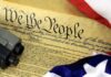 Close-up of the U.S. Constitution with a firearm and American flag