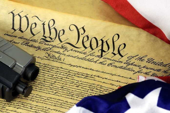 shutterstock_165794930.jpg Close-up of the U.S. Constitution with a firearm and American flag