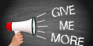 A hand holding a megaphone with the words GIVE ME MORE on a blackboard background