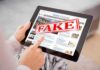 Person holding a tablet displaying a news website with a 'FAKE' stamp