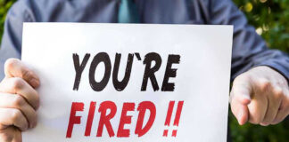 Person holding YOURE FIRED sign.