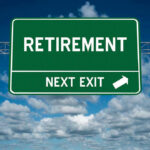 Green road sign reading retirement next exit sky background