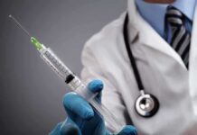 A doctor holding a syringe with a stethoscope around their neck