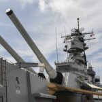 Close-up of a battleships naval guns and superstructure against a cloudy sky
