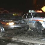 A damaged car and a police vehicle involved in a nighttime accident