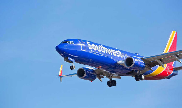 1014513529 Southwest Airlines plane flying in blue sky.
