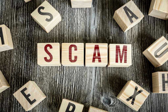 343236656 Wooden blocks spell SCAM on a rustic surface.
