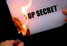 A hand holding a lighter igniting a paper labeled TOP SECRET as it catches fire