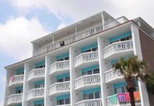 Exterior view of a beachfront hotel with balconies and colorful towels hanging