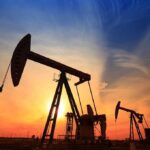 Silhouetted oil pumps against a colorful sunset sky