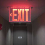 Red illuminated exit sign in a hallway.