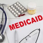 Medical documents with the word 'Medicaid' prominently displayed alongside a stethoscope and medication