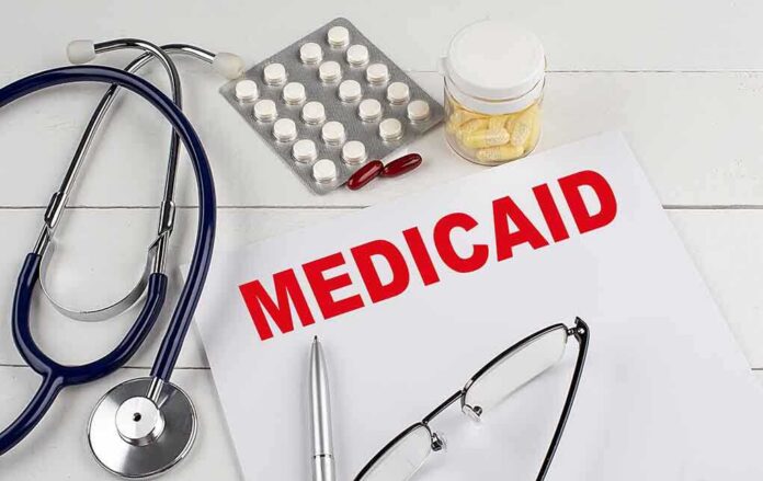 shutterstock_2201257403 Medical documents with the word 'Medicaid' prominently displayed alongside a stethoscope and medication